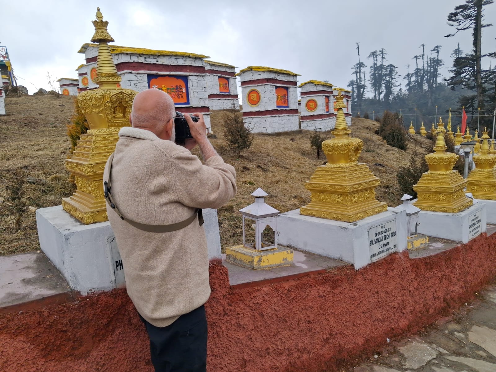 A photographer documenting golden Buddhist stupas on a high ridge above Tawang, Arunachal Pradesh