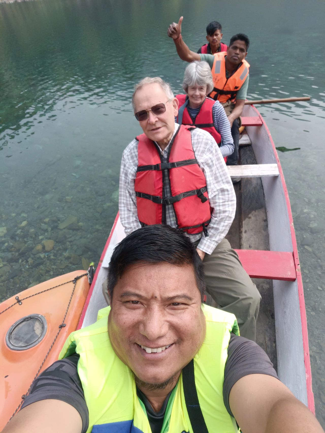 Guests on a wooden canoe over glass-clear river water